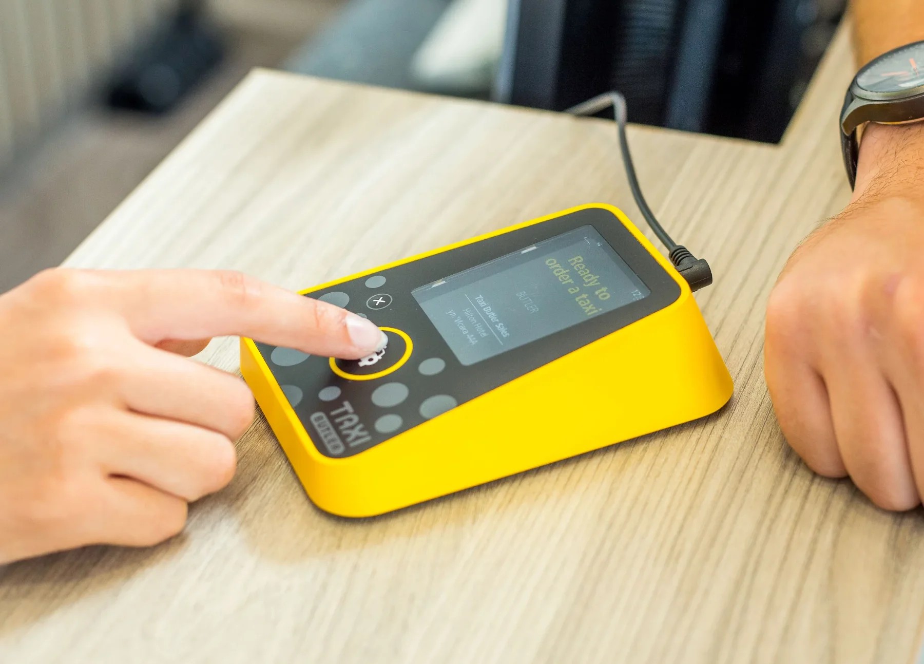 Concierge clicking on the Taxi Butler ONE taxi booking device to order a taxi for a guest